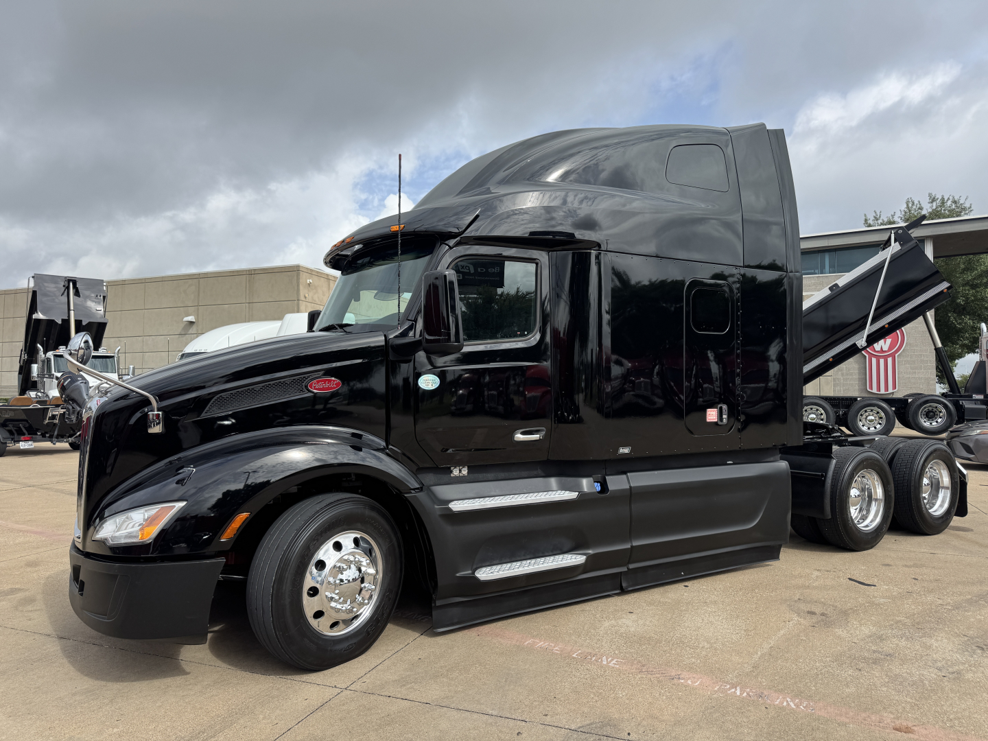 Peterbilt 579 tractor-trailer in black with sleeper cab, side view showing chrome fuel tanks and dual rear wheels.