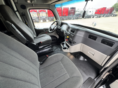 Peterbilt 579 cab interior showing driver seat, steering wheel, dashboard, and center console in a sleeper truck.