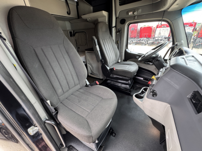 Truck cab interior of a 2023 Peterbilt 579 showing front seats and dashboard with steering wheel and center console.