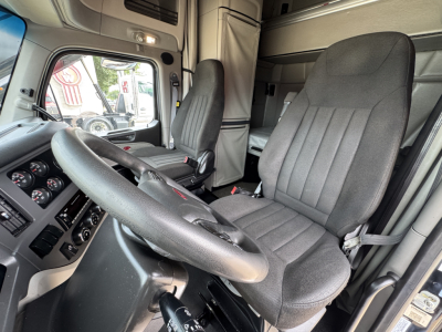 Peterbilt 579 truck interior showing steering wheel, driver's seat, dashboard gauges, and bunk area.
