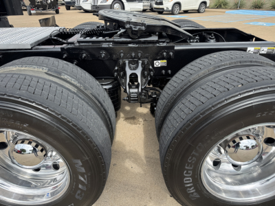 Dual rear tractor tires and fifth wheel hitch area of a Peterbilt 579 tractor showing dual wheels with Bridgestone tires and chrome hubcaps, undercarriage frame and προσ