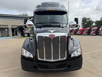 Peterbilt 579 truck front view showing chrome grille, large headlights, and side mirrors in a parking lot.