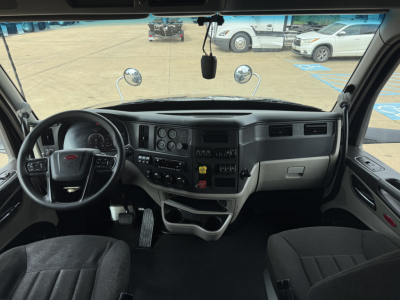 Peterbilt 579 truck interior showing steering wheel, dashboard, and driver seat with instrument cluster and center console.