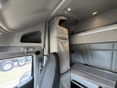 Truck sleeper cab interior of a 2023 Peterbilt 579 showing upper bunk and side storage with light gray interior panels.