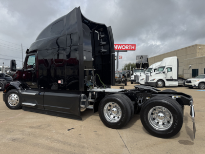 Peterbilt 579 tractor cab side view showing chrome dual rear axles and raised sleeper with black paint.