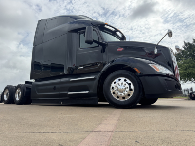 Peterbilt 579 truck side view showing sleeper cab, black paint, front fender, wheel, and chrome hubcap.
