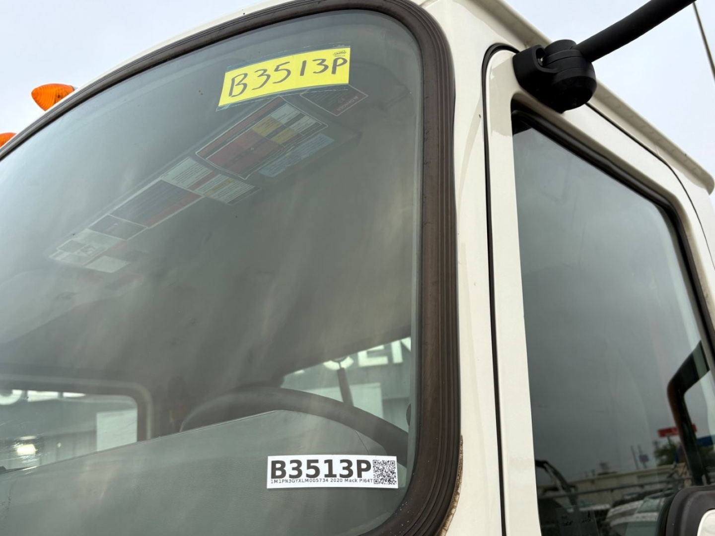 Truck cab window with B3513P sticker, 2020 Mack PI64T listing details visible on windshield label.