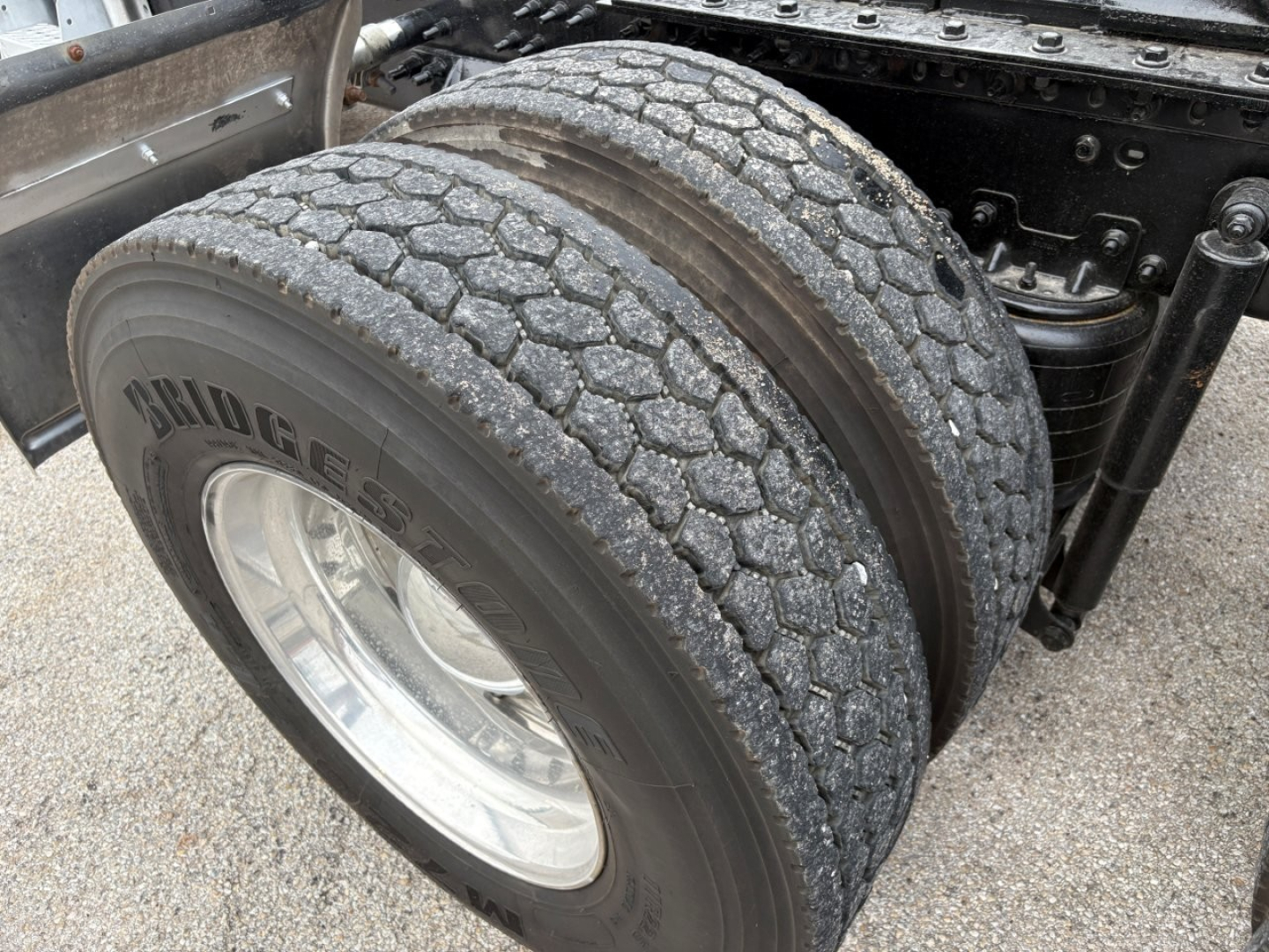 Mack PI64T truck rear dual tires showing tread pattern and wheel, with part of the chassis and suspension visible.