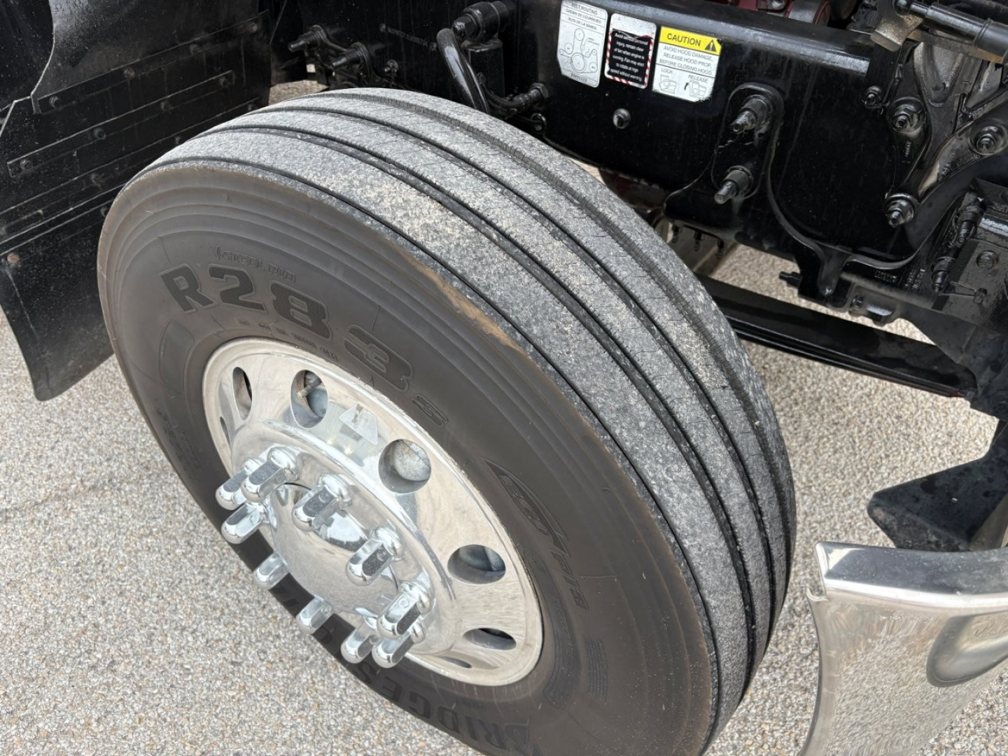 Mack PI64T truck front wheel view showing dual rear-axle? front dual tires R28 label on tire tread with wheel hub and brake components visible.