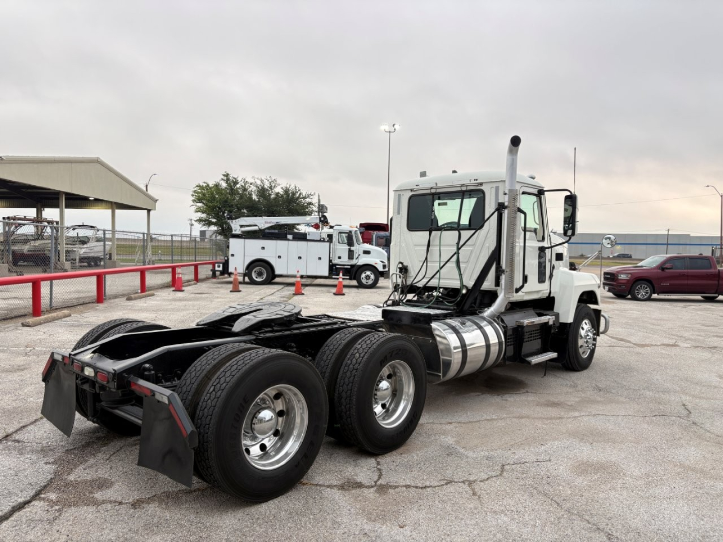 Mack PI64T conventional daycab tractor showing rear wheel area and exhaust stack with fuel tanks, 3-axle configuration, VIN plate not visible.