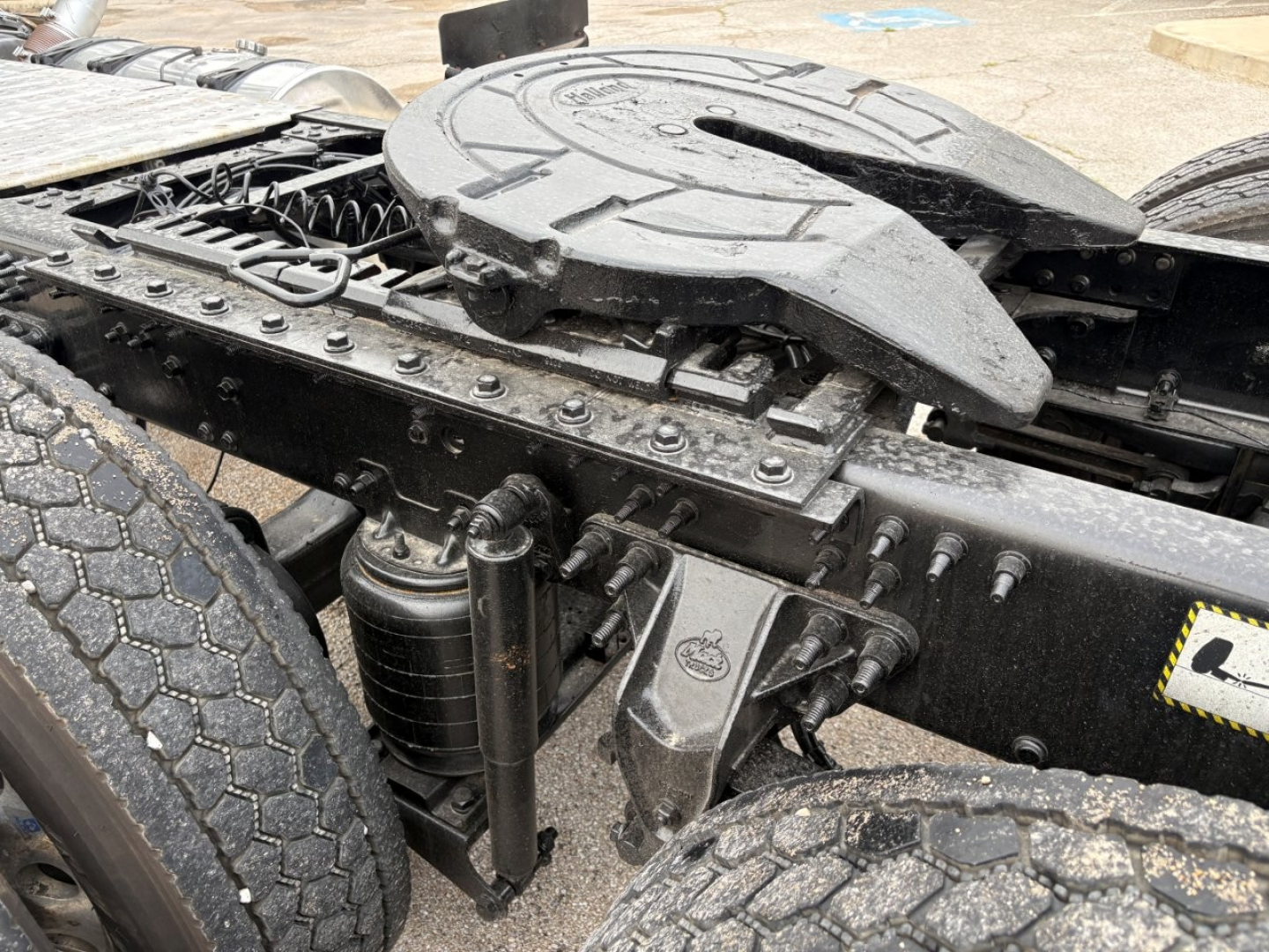 Tractor cab chassis area of a 2020 Mack PI64T showing drivetrain U-bolt area, hydraulic lines, frame Rails, and fifth wheel base with components.