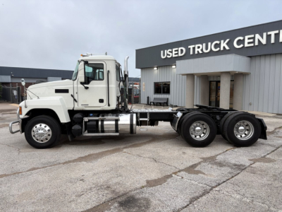 2020 Mack PI64T conventional daycab truck chassis shown in side profile with cab and dual rear axles, at used truck center facility.