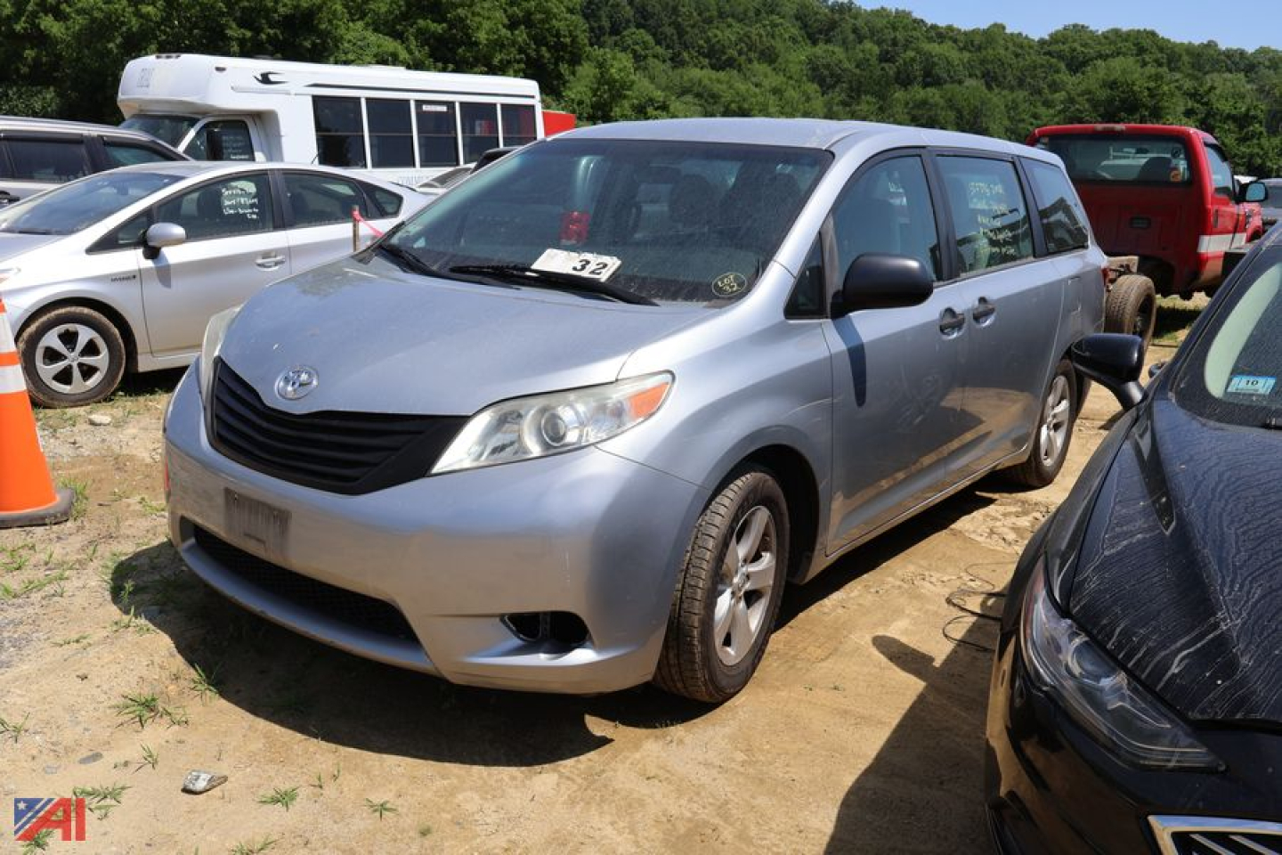 Front-left view of a silver 2016 Toyota Sienna minivan in a lot, showing the grille, headlights, and side profile with other vehicles in background.