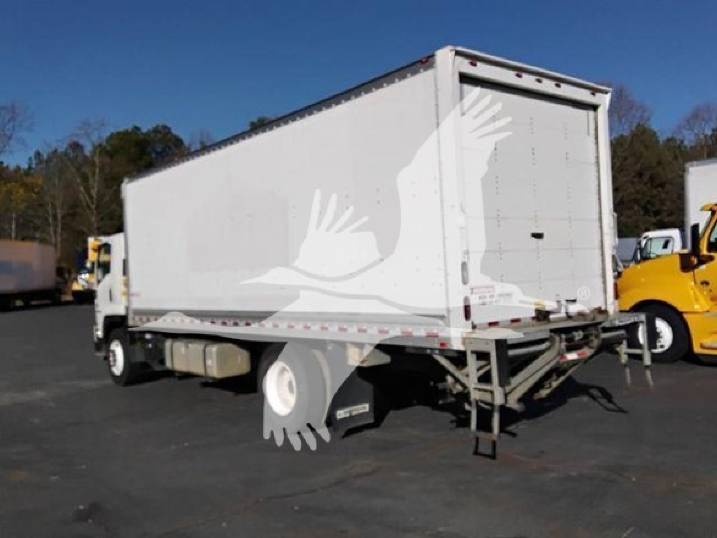 Isuzu box truck rear/side view showing cargo area with liftgate and warning decals.