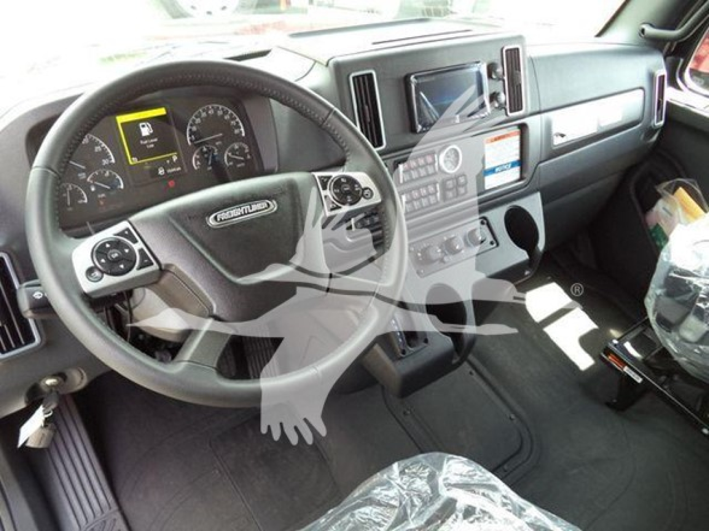 Freightliner M2 106 cab interior showing steering wheel, dashboard, touchscreen display, and center console.