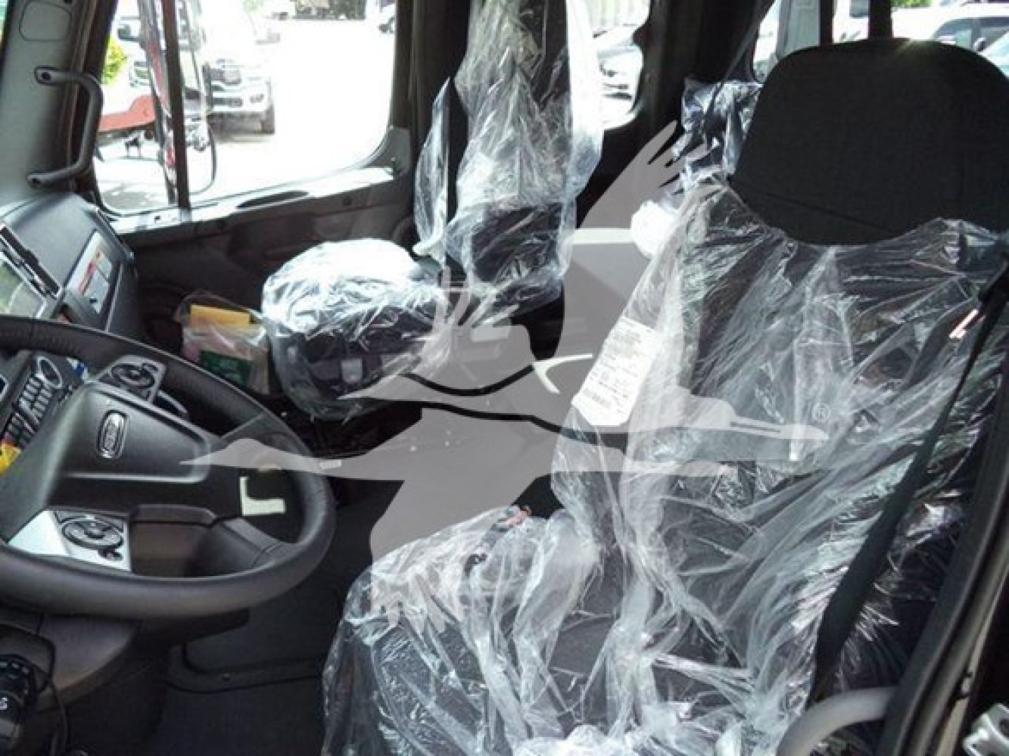 Truck cab interior of a 2027 Freightliner M2 106 with plastic-covered seats and dashboard visible