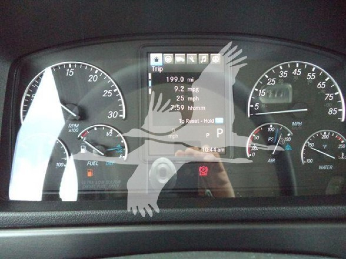 Dashboard display of a Freightliner M2 106 showing instrument cluster and digital trip data including 199.0 mi, 9.2 mpg, 25 mph, and P gear with tachometers and gauges.