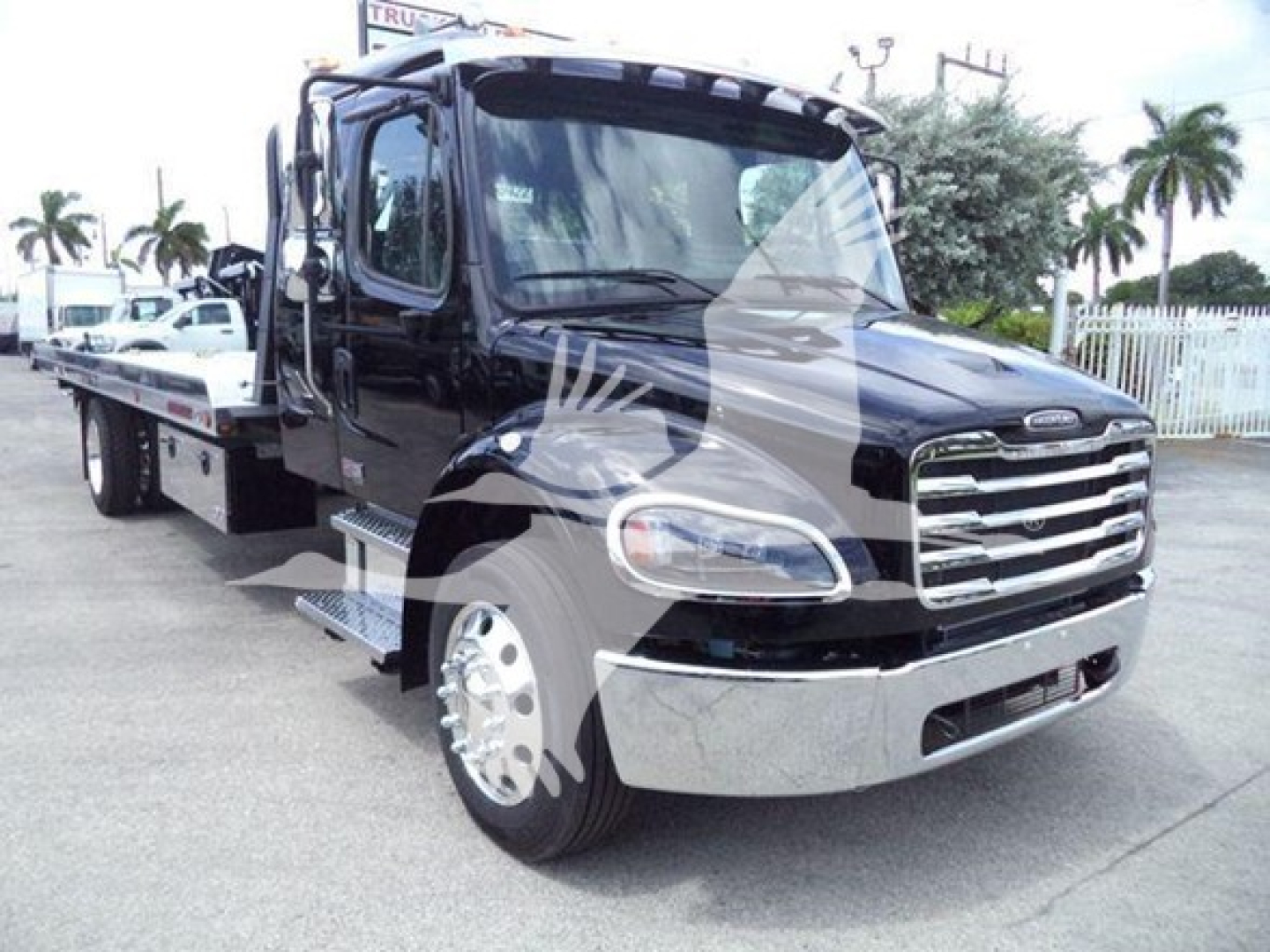 Freightliner M2 106 rollback truck front view showing chrome grille and black cab.