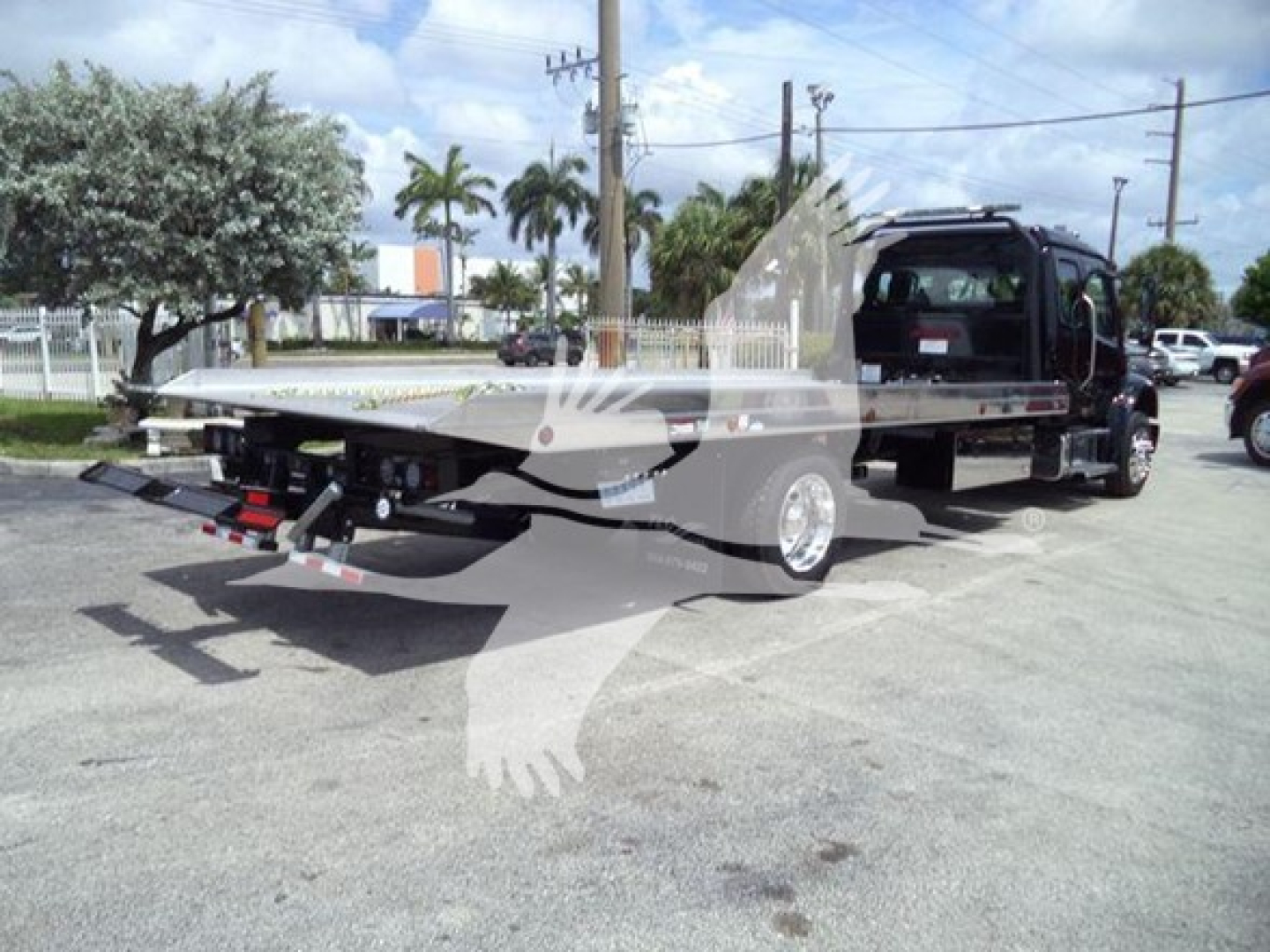 2027 Freightliner M2 106 rollback tow truck with flatbed and wheel-lift showing rear view and cab in background