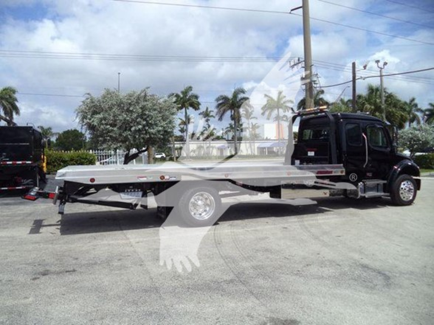 Freightliner M2 106 rollback truck in side view with flatbed and black cab, wheel and hydraulic equipment visible.