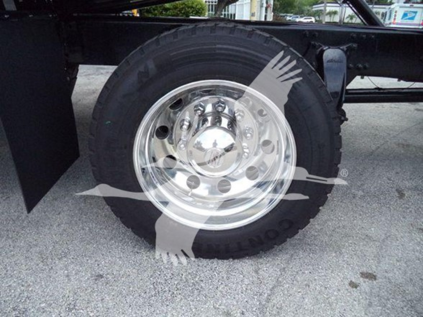 Wheel and tire assembly of a Freightliner M2 106 rollback showing chrome hubcap and polished rim with attached wheel components.