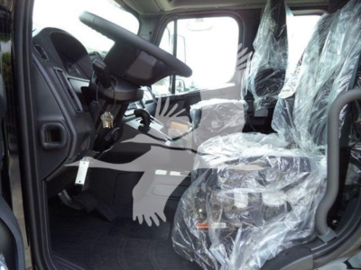 Cab interior of a 2027 Freightliner M2 106 roll-back truck showing plastic-wrapped seats, steering wheel, and pedals.