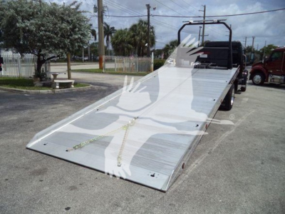 Truck ramp-back view showing aluminum rollback bed on a Freightliner M2 106 with hydraulic ramps and chain tie-downs.