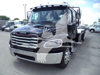 Freightliner M2 106 rollback truck shown head-on, black cab with chrome grille and side mirrors, hydraulic tow bed visible.