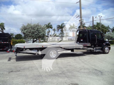 Freightliner M2 106 rollback truck in side view with flatbed and black cab, wheel and hydraulic equipment visible.