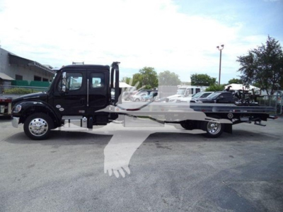 Freightliner M2 106 rollback truck side view showing tow rig with black cab and long flatbed.