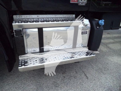 Truck side step with chrome fuel tank and black cab; visible steps and a blue cap near the running board.