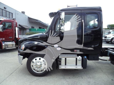 Freightliner M2 106 truck cab side view showing chrome steps and wheel, black body with decals, diesel engine bay area.