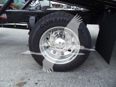 Truck wheel and fender area showing a heavy-duty tire with chrome rim and hub, undercarriage of a Freightliner M2 106 rollback truck.