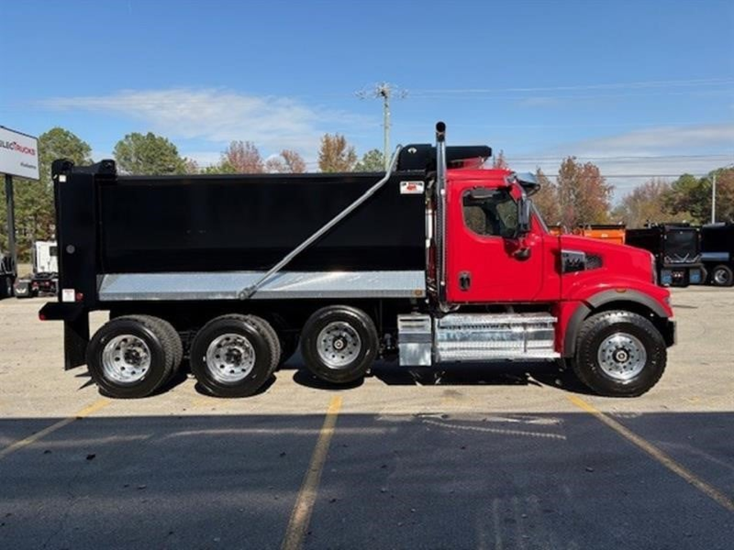 Western Star 49X dump truck side view showing red cab and black dump body with dual rear wheels.