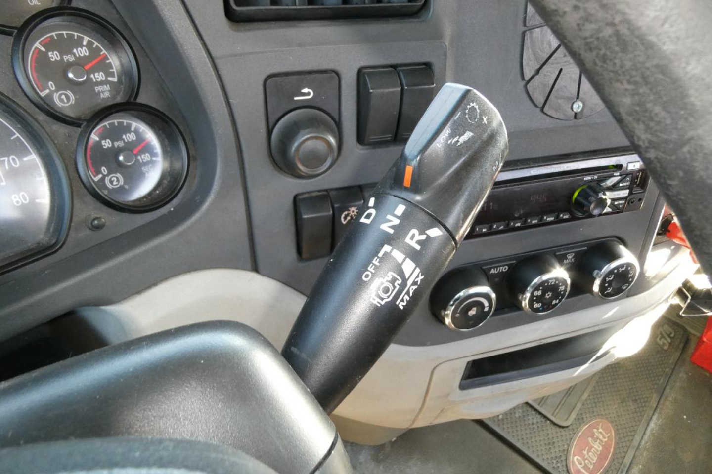 Peterbilt 579 interior view showing steering column with gear selector stalk, dashboard gauges, and climate controls.