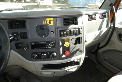 Peterbilt 579 dash close-up showing instrument cluster, control switches, and HVAC vents in a daycab truck interior.