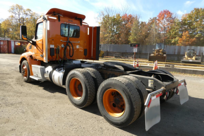 Peterbilt 579 tractor in orange color, side view showing rear dual wheels and chassis
