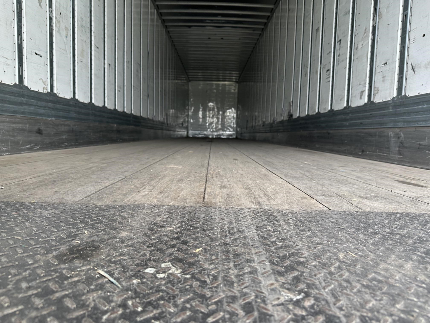 Inside view of a 2019 Utility 4000D-X trailer cargo space with wooden floor and metal side walls.