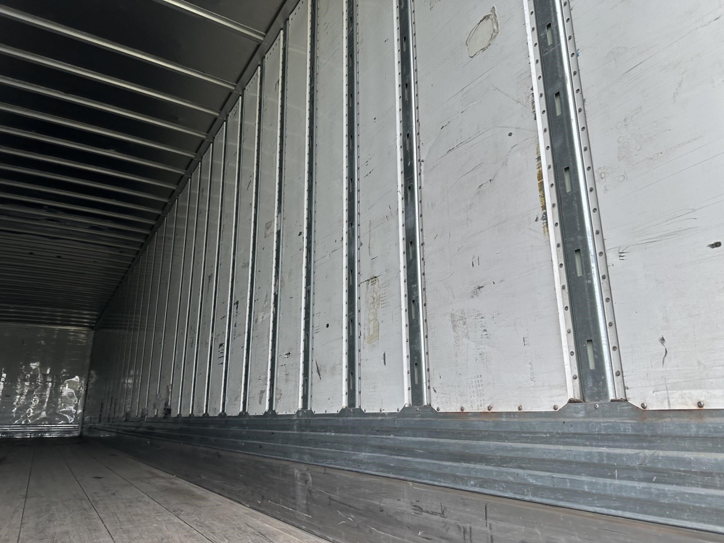 Utility 4000D-X trailer interior with aluminum sidewalls and ribbed floor, showing metal joists along the walls.