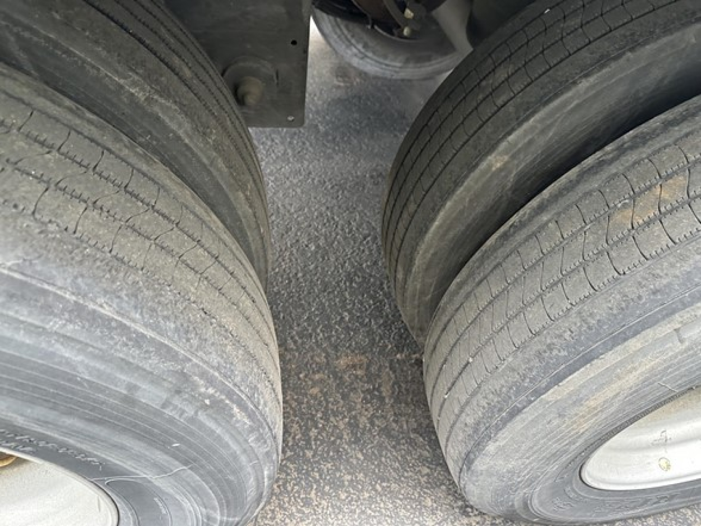 Trailer tires with dual rear wheels, road grime on the tread, showing the gap between axles under a Utility 4000D-X trailer.