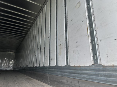 Trailer interior side wall and floor of a used 2019 Utility 4000D-X trailer showing metal ribbed walls and wooden floor edges.