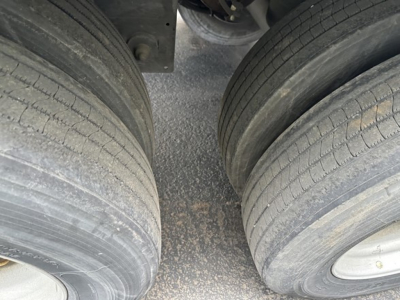 Trailer tires with dual rear wheels, road grime on the tread, showing the gap between axles under a Utility 4000D-X trailer.