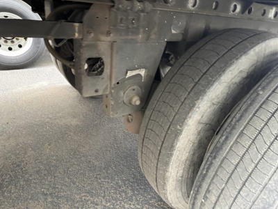 Trailer undercarriage with dual rear tires and mounting hardware showing metal frame and suspension components.