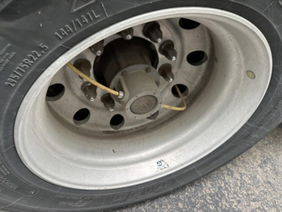 Wheel and tire assembly of a Utility 4000D-X trailer showing steel rim, lug nuts, and valve stem.