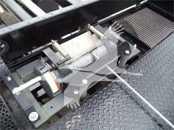 Winch assembly mounted on diamond plate flooring with steel cable and hawser drum, clevis pins, and hydraulic winch body.