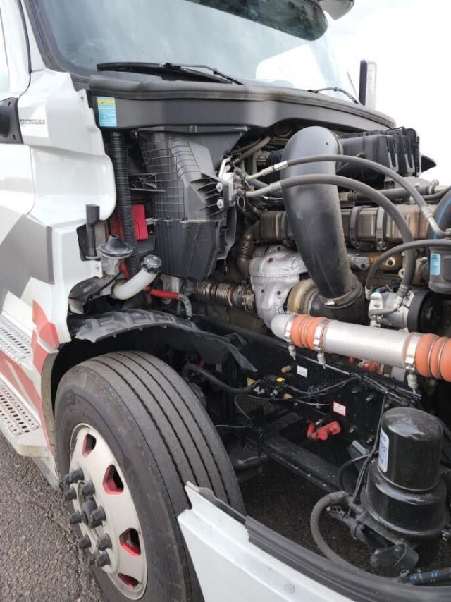 Freightliner Cascadia engine bay showing radiator, hoses, and turbocharger with front wheel visible