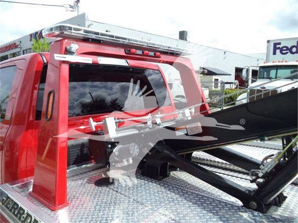 Truck bed area with red cab, chrome diamond plate surface, tow equipment and rack; visible text includes 'RAM' on tailgate and potential model labeling on tags but not fully legible.