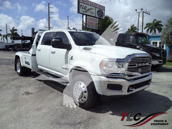 Ram 5500 Tow truck front three-quarter view showing chrome grille, dual rear wheels, and listing details in background.