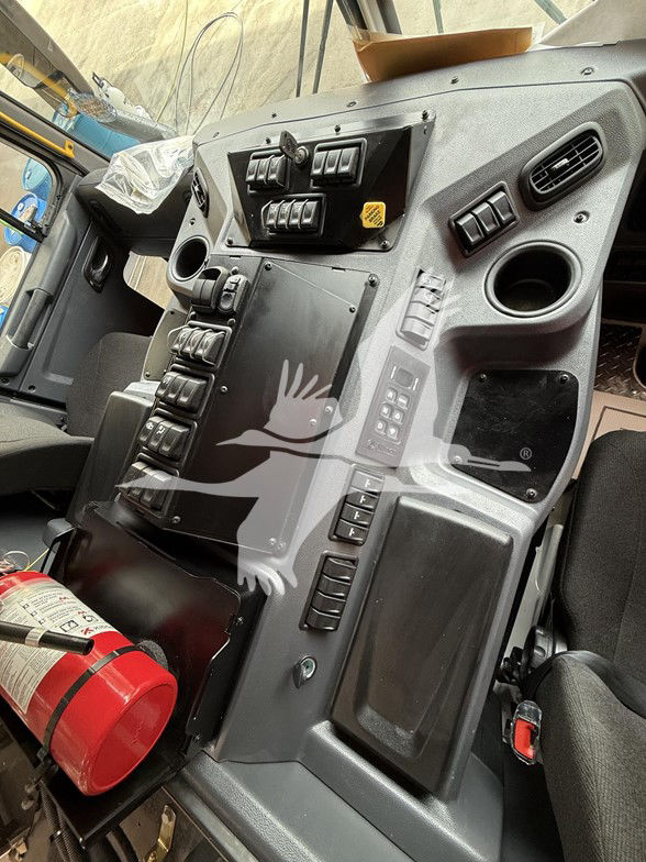 Kenworth L770 cab interior dashboard with multiple switches, control panels, circular vents, and a red fire extinguisher in the lower left.