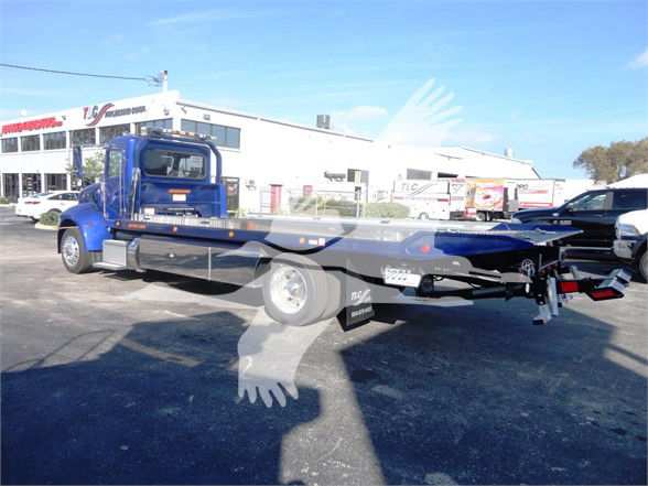 Tow truck chassis in blue, 2022 Peterbilt 337 roll-back flatbed with extended bed and winch, side view.
